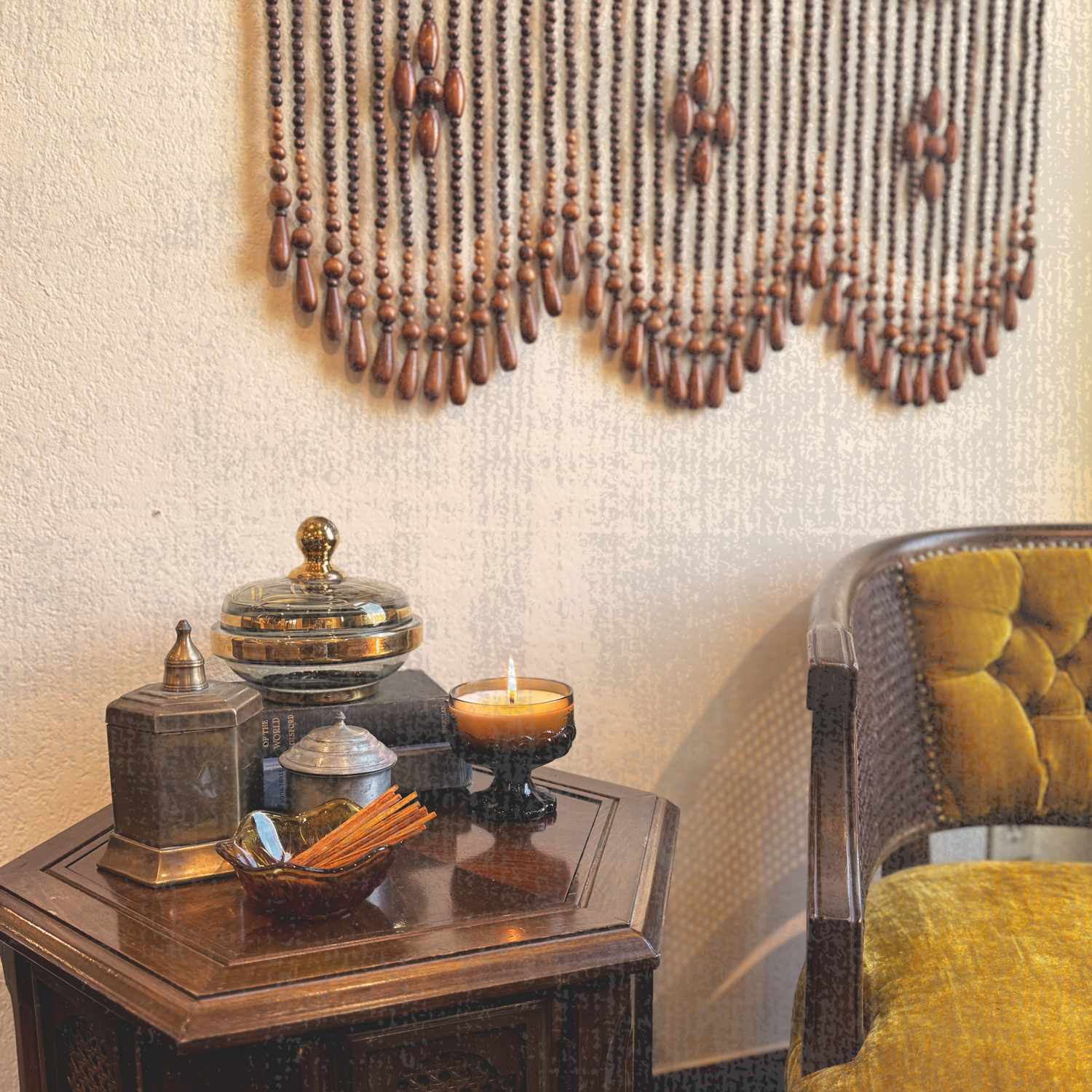 Metal and glass candles decorate a wooden side table and chair with beaded backdrop